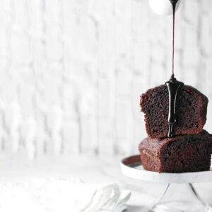 Delicious chocolate cake with rich sauce dripping on a white cake stand. Perfect for dessert lovers.