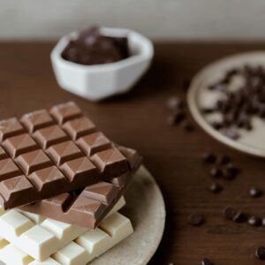 High angle of delicious bars of chocolate on plate on wooden table with scattered chocolate chips