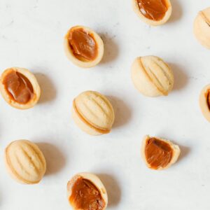 Top view of traditional Russian oreshki cookies with caramel filling on a white background.